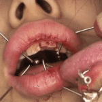 Painfuls BDSM lesbian kiss with needles in lips.