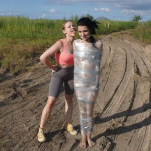 Undressed girl wrapped with duct tapa and saran wrap in a field